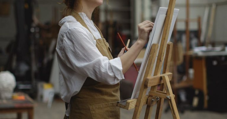 Visual Boards - Young Woman in Brown Apron Sketching on White Cardboard