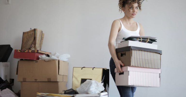 Clutter - Concentrated woman carrying stack of cardboard boxes for relocation