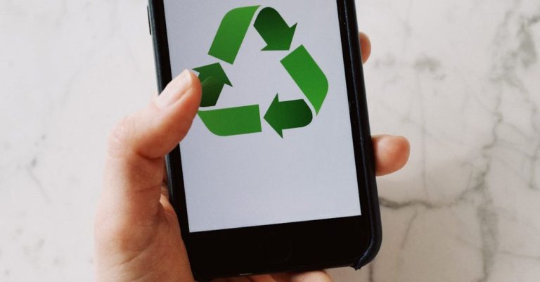 Labeling System - From above view of crop hand showing mobile phone with green recycle icon on white background above marble table